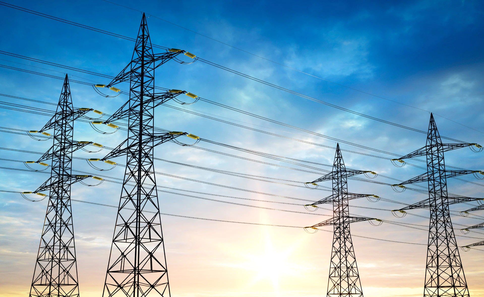 Torres de transmisión eléctrica y líneas de alta tensión recortadas contra el cielo al atardecer